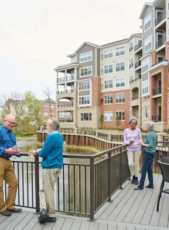 2 men talking and 2 women walking outside near lake