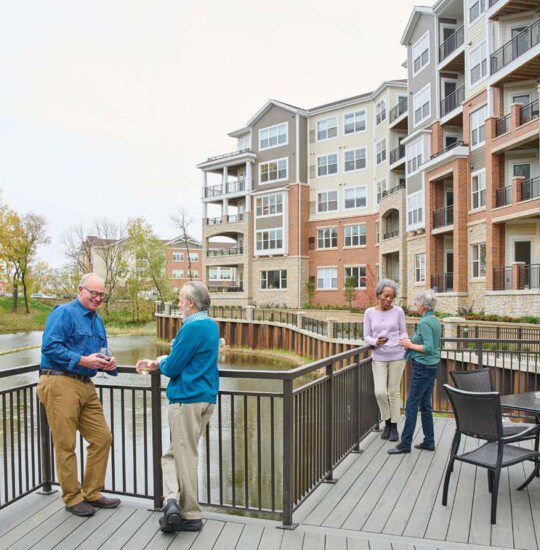 2 men talking and 2 women walking outside near lake