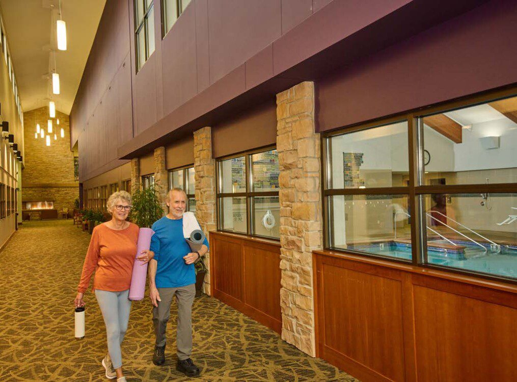 women with yoga mats walking by indoor pool