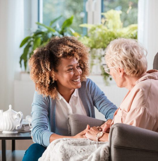 young woman smiling at older woman sitting in chair