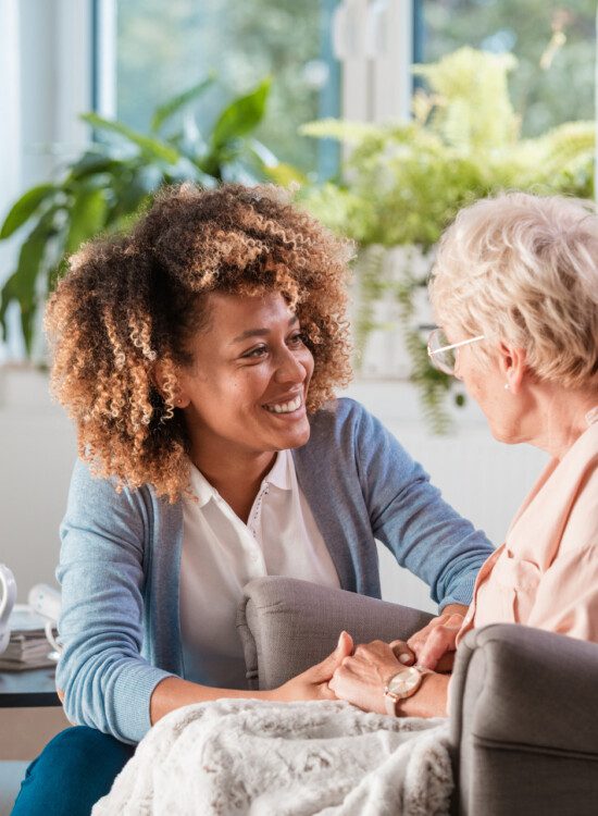 young woman smiling at older woman sitting in chair