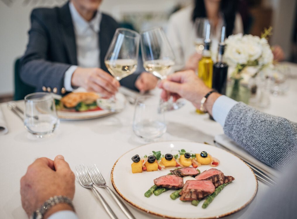 wine glasses touching at table of food