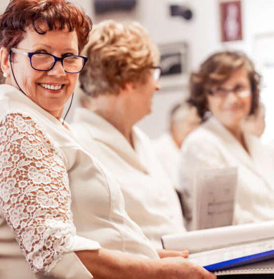 woman reading book smiling next to 2 other women